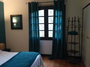 a bedroom with a bed and a window with blue curtains at Bienvenue ! in Moissac
