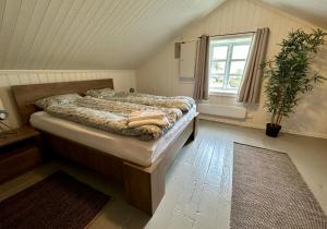 a bedroom with a bed and a window and a tub at Storhella - Feriehus med fantastisk beliggenhet in Sennesvik