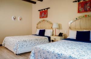 a bedroom with two beds with blue and white sheets at Uzhupud Garden Hotel & Lodge in Paute