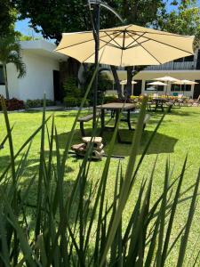 einen Picknicktisch mit einem Sonnenschirm im Hof in der Unterkunft Hotel Boutique Luciérnaga in Chiconcuac