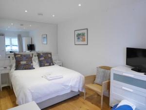 een slaapkamer met een bed, een televisie en een stoel bij Apartment with Roof Terrace - Centre of Yarmouth in Yarmouth