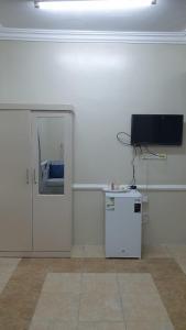 a white room with a television and a small refrigerator at سويتات مفروشة in Al Hofuf