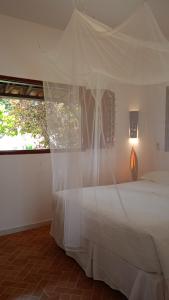 a bedroom with a bed with a mosquito net at Pousada Vila Caju in São Miguel do Gostoso