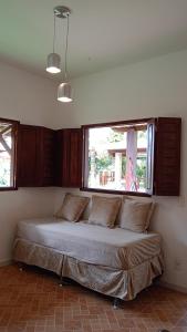 Bett in der Ecke eines Zimmers mit Fenster in der Unterkunft Pousada Vila Caju in São Miguel do Gostoso