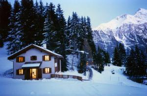 a house in the snow with lights on at Acla Pala in Lenzerheide