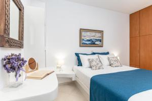 a white bedroom with a bed and a vase of flowers at Amaranto Naxos in Naxos Chora