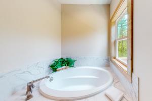a bathroom with a large white tub and a window at Woodstone Trail Tranquility in Ellijay +31 photos