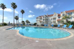 a large swimming pool with chairs and palm trees at Casa Del Sol in Padre Island