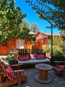 a bench with pillows and a table in a yard at Cabañas Refugio Nativo in Santa Cruz