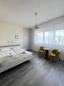 1 dormitorio con 1 cama, 2 sillas y mesa en Wolf Panzió, en Sárvár