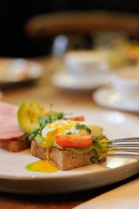 um prato com uma sanduíche de ovo numa mesa com um garfo em Mamma´s Boutique Hotel em Poděbrady