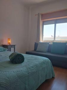 a bedroom with a bed and a couch and a window at Navigation House in Sesimbra