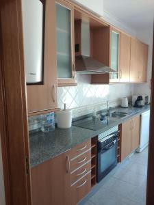 a kitchen with wooden cabinets and granite counter tops at Navigation House in Sesimbra +7 photos