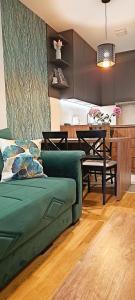a living room with a green couch and a table at Apartman 49 in Subotica