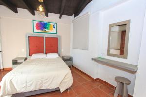 a bedroom with a bed and a mirror and a stool at Hotel Casa Autora 40 in Guanajuato
