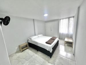 a white bedroom with a bed and a window at APARTAMENTO 401 MEDELLIN in Medellín
