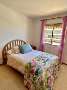 een slaapkamer met een bed met een bloemenbed en een raam bij Vista al mar - Piscina by VV Canary Ocean Homes in Los Cristianos