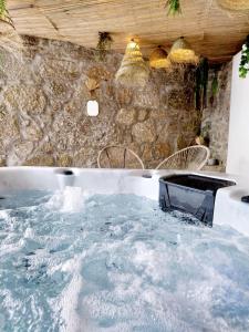 a hot tub in a room with a stone wall at Lodges Minho in Ponte da Barca