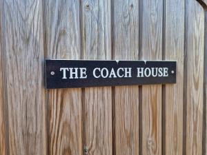 um sinal que lê a estalagem pendurada numa cerca de madeira em The Coach House em Hawkhurst