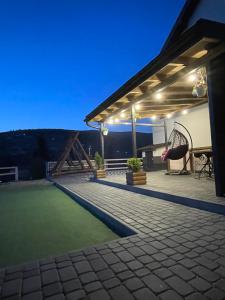 a patio with a roof with a table and a swing at Приватна садиба Соломія in Bukovel