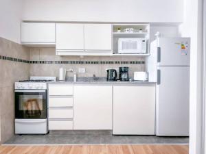 una cocina blanca con armarios y electrodomésticos blancos en Jufre I - Amazing Studio in Palermo Soho en Buenos Aires