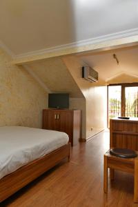 Schlafzimmer mit einem Bett, einem TV und einem Tisch in der Unterkunft Antika Hotel in Batumi