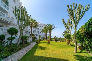 a garden in front of a building with palm trees at Stella Maris B Casasol Apartments in Nerja