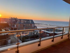 - un balcon avec vue sur l'océan et les bâtiments dans l'établissement Golden Hour Apartment Wangerooge, à Wangerooge