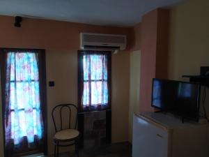 a living room with a tv and two windows at Double studio room with two single beds in Tsagarada