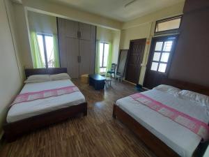 um quarto de hotel com duas camas e duas janelas em GIFTLAND HOMESTAY em Āīzawl
