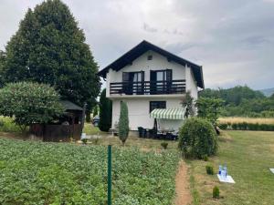 a white house with a balcony and a yard at Zelena dolina-Green Valley in Travnik