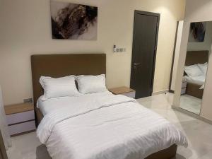 una camera da letto con un grande letto con lenzuola bianche di Urban Haven - Surulere a Lagos