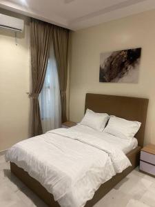 1 dormitorio con 1 cama con sábanas blancas y ventana en Urban Haven - Surulere, en Lagos