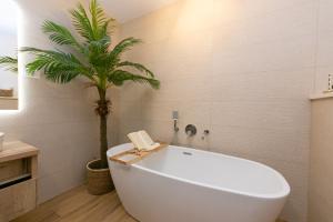 a white bath tub in a bathroom with a palm tree at Apartment Vidra in Brela +22 photos