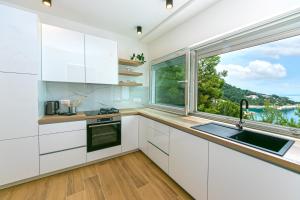 Apartment Vidra في بريلا: مطبخ مع دواليب بيضاء ونافذة كبيرة