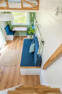 a tiny house with a blue couch in a room at Green Tiny House with shared pool in Zeewolde