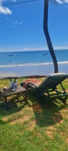 a picnic table and a chair next to a beach at Suíte pé na areia in Icapuí