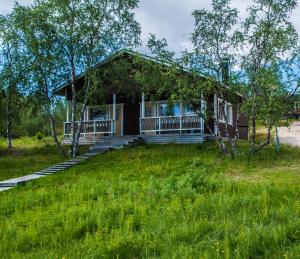 ein kleines Haus mit einer Veranda und einem Rasenplatz in der Unterkunft Tunturikeskus Galdotieva in Leppäjärvi