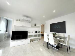 ein weißes Wohnzimmer mit einem Tisch und einem TV in der Unterkunft Domuum Holidays - BARCELONA Family Home in Salou