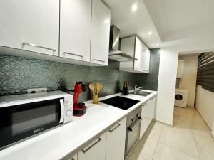 a kitchen with white cabinets and a sink at Domuum Holidays - BARCELONA Family Home in Salou