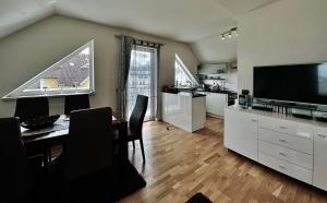 a living room with a table and a kitchen with a television at Superior-Apartment mit Pool und Seezugang in Velden am Wörthersee