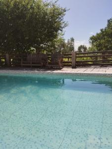a swimming pool with two benches in front of a fence at El RANCHO in San Martín