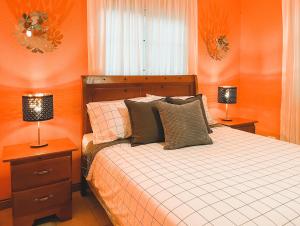 Casa del Arroyo 2-Bedroom Cottage Fireplace and BBQ في جاراباكو: غرفة نوم بجدران برتقالية وسرير به مصباحين