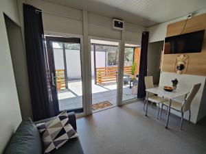 ein Wohnzimmer mit einem Tisch und Stühlen sowie einem Balkon in der Unterkunft ARIA Mobile Home, Oaza Mira 5 Star Camping, Dalmatia in Drage