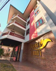 a hotel with a yellow sign on the side of a building at CHORLADA LANNA HOTEL in Chiang Mai