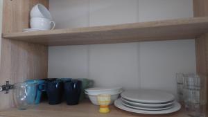 a kitchen shelf with plates and cups and bowls at Comfy room near city centre in Tallinn