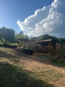une grande cabane en bois avec une terrasse couverte dans un champ dans l'établissement La Cabane de Mercone Crenu, à Corte