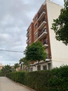 an apartment building with a tree next to a sidewalk at Habitación privada in Valencia