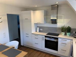 a kitchen with white cabinets and a stove top oven at Apartment im alten Rathaus in Malterdingen