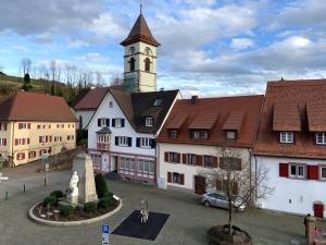 a building with a clock tower in a town at Apartment im alten Rathaus in Malterdingen